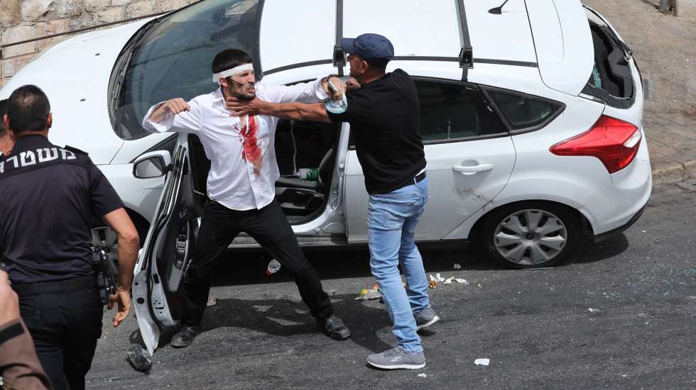 epa09189000 Palestinians scuffle with a wounded Orthodox Jewish man (C) who crashed his car near the Lions' Gate, while police (L) intervene as clashes continue at the Temple Mount in the old city of Jerusalem, 10 May 2021. Protests continue in support of six Palestinian families facing eviction in the neighborhood of Sheikh Jarrah in favor of Jewish families who claimed they used to live in the houses before fleeing in the 1948 war that led to the creation of Israel. Thousands of Israelis, including right-wing groups, were expected to join the 'Flag March' on 10 May which is considered 'Jerusalem Day', an Israeli national holiday that celebrates the establishment of Israeli control over the Old City in the aftermath of the June 1967 Six-Day War.  EPA/ABIR SULTAN QUALITY REPEAT