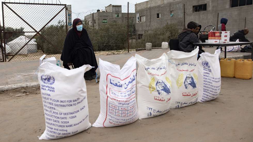 epa11110540 A Palestinian woman stands next to flour bags distributed by UNRWA (United Nations Relief and Works Agency for Palestine Refugees in the Near East) in Rafah, southern Gaza Strip, 28 January 2024. Several Western countries have suspended or reviewed funding to the UN agency for Palestinians following Israel’s allegations that some UNRWA staff members had been involved in the 07 October 2023 Hamas attacks.  EPA/HAITHAM IMAD