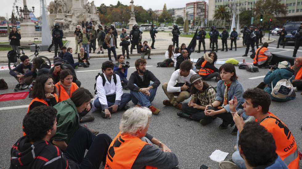 Portuguese activists sit on at Marques de Pombal Square during a climate change rally in Lisbon, Portugal, 09 December 2023. Organized by Climáximo, the demonstration under the motto “In a state of climate emergency, resist for life” aims to discuss the proliferation of weapons of mass destruction and the deactivation of weapons of mass destruction. TIAGO PETINGA/LUSA