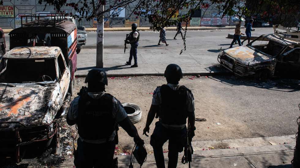 epa11200677 Police guard the exterior of the Carrefour Aeroport police station, which was set on fire on 04 March by gang members, in Port-au-Prince, Haiti, 05 March 2024. The streets of Port-au-Prince show apparent normality after the intense shootings the day before, although in some places bodies continue to appear. The population tries to recover normality and dedicates themselves to their daily tasks, despite the fact that on their way, as EFE was able to verify, they come across corpses that some people cover with a blanket, while others are simple charred remains.  EPA/JOHNSON SABIN