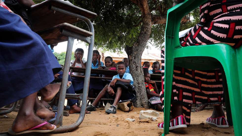 epa09134712 A teacher gives a lesson to the students at the open-air classes at the primary school in the neighborhood of Mahate, in Pemba, Cabo Delgado province, Mozambique, 14 April 2021. The classes are performed outside due to the lack of rooms for the approximately 2000 students, of which 500 are internally displaced. The school is supported by the NGO Helpo through the Karibu Foundation. The violence unleashed more than three years ago in Cabo Delgado province escalated again about two weeks ago, when armed groups first attacked the town of Palma, forcing people to flee from a conflict zone.  EPA/JOAO RELVAS