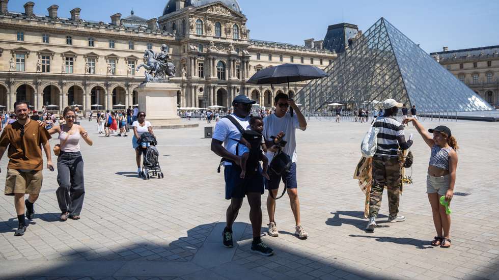 epa13068977 People walk under an umbrella in the courtyard of the Louvre Museum in Paris, France, 27 June 2026, amid high temperatures. The museum adjusted its opening hours because of the heatwave, as France experienced unusually high temperatures for the time of year since the start of the week.  EPA/CHRISTOPHE PETIT TESSON