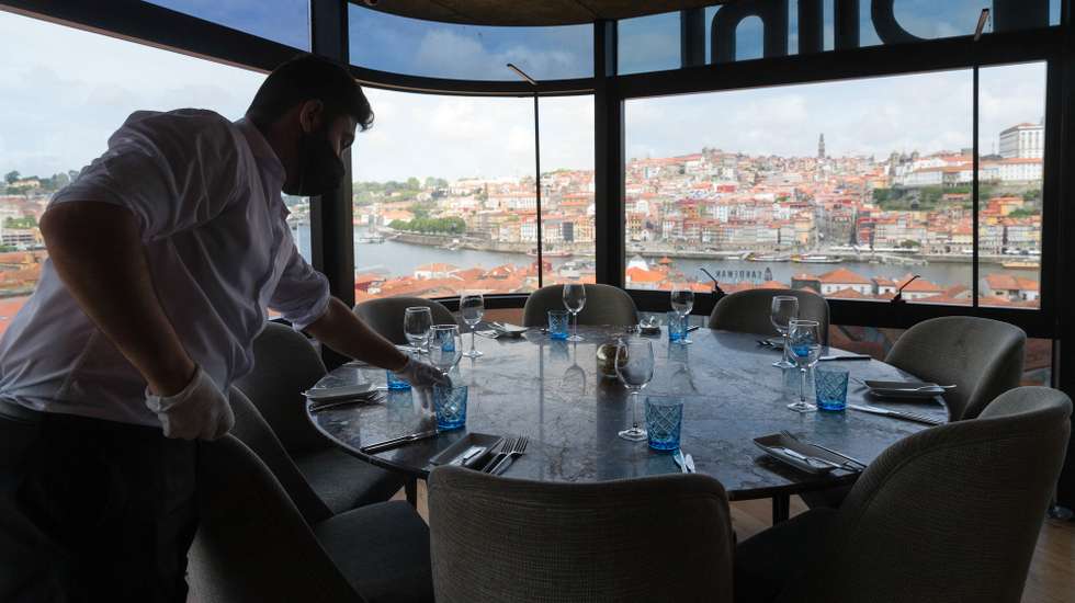 Um funcionário prepara uma mesa no restaurante The Blini no dia em que entram em vigor novas medidas de desconfinamento, Vila Nova de Gaia, 19 de abril de 2021. Passa a ser autorizada a abertura de restaurantes, cafés e pastelarias, mas com a restrição de lotação máxima a quatro pessoas ou seis pessoas em esplanadas e com horário até às 22:00 horas ou às 13:00 ao fim de semana. JOSÉ COELHO/LUSA