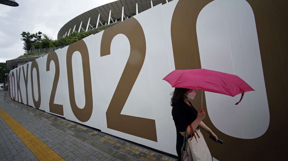 epa09294865 A passerby walks past the National Stadium, the main stadium of the 2020 Tokyo Olympic Games, in Tokyo, Japan, 23 June 2021, one month before the opening of the Tokyo 2020 Olympic Games. The National Stadium will host the opening, closing ceremonies and the athletics events. The Summer Games were postponed due to COVID-19 Coronavirus pandemic.  EPA/FRANCK ROBICHON