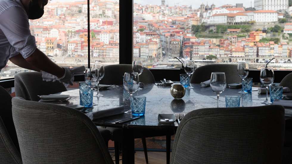 Um funcionário prepara uma mesa no restaurante The Blini no dia em que entram em vigor novas medidas de desconfinamento, Vila Nova de Gaia, 19 de abril de 2021. Passa a ser autorizada a abertura de restaurantes, cafés e pastelarias, mas com a restrição de lotação máxima a quatro pessoas ou seis pessoas em esplanadas e com horário até às 22:00 horas ou às 13:00 ao fim de semana. JOSÉ COELHO/LUSA