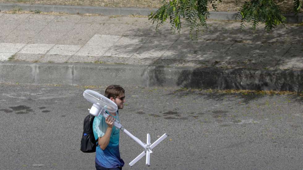 Um homem, transporta uma ventoinha, numa rua de Lisboa, 4 Agosto 2018. Portugal continental está debaixo de calor extremo até final do dia de sábado, com 11 distritos sob aviso vermelho, o mais grave, devido a um anticiclone que transporta ar quente do norte de África. ANTÓNIO COTRIM/LUSA