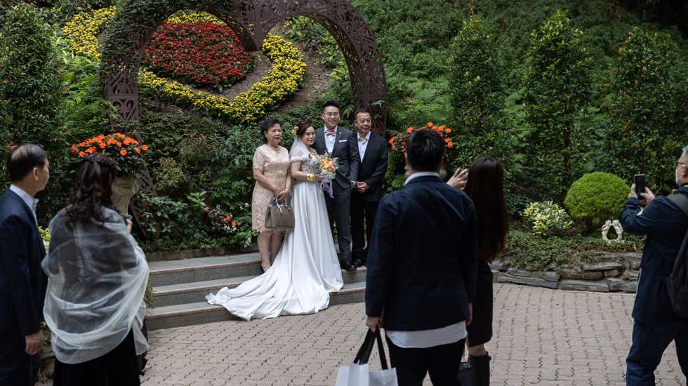 epa10465969 A newly wed couple poses for photos outside the Marriage Registry in Hong Kong China, 14 February 2023. Valentine's Day is considered an auspicious day to get married in the city.  EPA/JEROME FAVRE