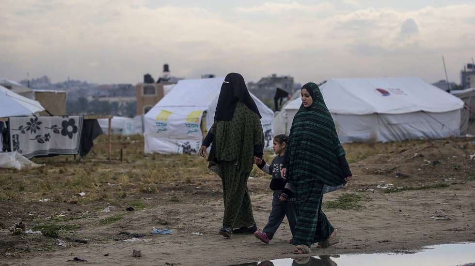 epa11164825 Displaced Palestinian women from Rafah walk next to their shelters in Deir Al Balah, southern Gaza Strip, 18 February 2024. More than 28,900 Palestinians and over 1,300 Israelis have been killed, according to the Palestinian Health Ministry and the Israel Defense Forces (IDF), since Hamas militants launched an attack against Israel from the Gaza Strip on 07 October 2023, and the Israeli operations in Gaza and the West Bank which followed it.  EPA/MOHAMMED SABER