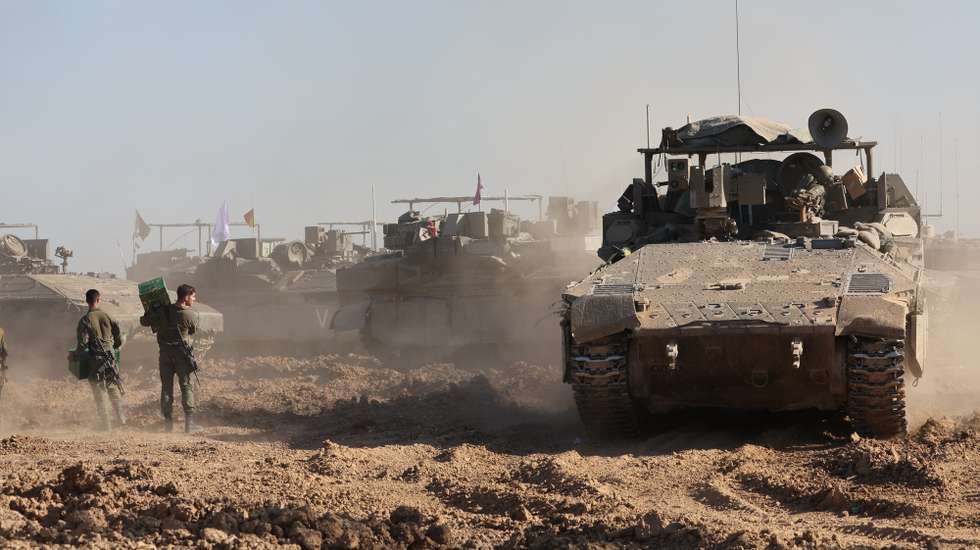 epa11211360 Israeli soldiers walk next to their military vehicles near the border fence with the Gaza Strip, as seen from the Israeli side in southern Israel, 10 March 2024. More than 31,000 Palestinians and over 1,300 Israelis have been killed, according to the Palestinian Health Ministry and the Israel Defense Forces (IDF), since Hamas militants launched an attack against Israel from the Gaza Strip on 07 October 2023, and the Israeli operations in Gaza and the West Bank which followed it.  EPA/ABIR SULTAN