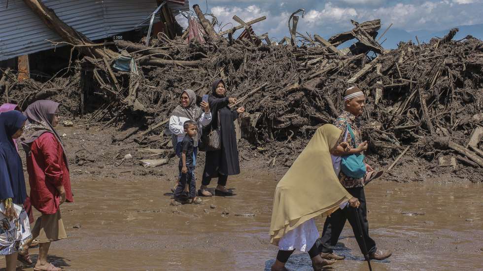epa11334644 Villagers wade through mud flooded area following a flash flood in Tanah Datar, West Sumatra, Indonesia, 12 May 2024. At least 13 people were killed after heavy rain triggered flash floods and cold lava flow from Merapi volcano according to the National Board for Disaster Management (BNPB).  EPA/GIVO ALPUTRA