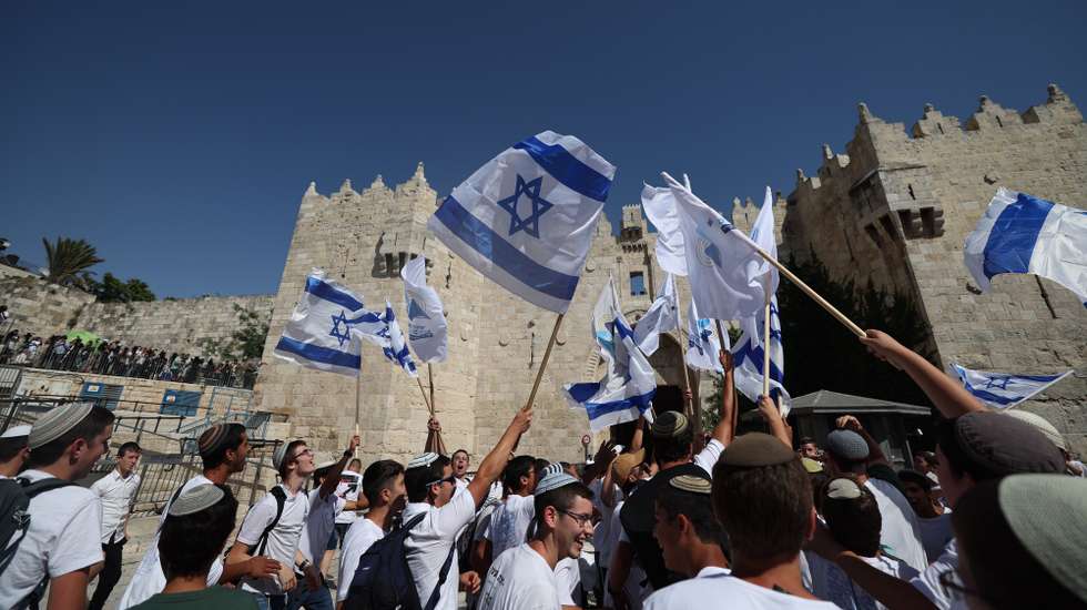epa11391190 People wave Israeli flags during the controversial 'Flag March' at the Damascus Gate in the Old City in Jerusalem, 05 June 2024, as Israel marks its national holiday of Jerusalem Day which commemorates the 'reunification' of Jerusalem as Israel took control of the old city of Jerusalem and East Jerusalem following the Six-Day War of 1967.  EPA/ATEF SAFADI