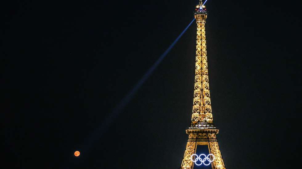 epa11555731 Super Blue Moon rises behind Eiffel Tower and Olympic rings, as seen from Place du Trocadero, in Paris, France, 19 August 2024. The term 'supermoon' is used to describe when the full moon coincides with the Moon's closest approach to Earth on its elliptical orbit and therefore appears brighter and larger than usual.  EPA/Mohammed Badra