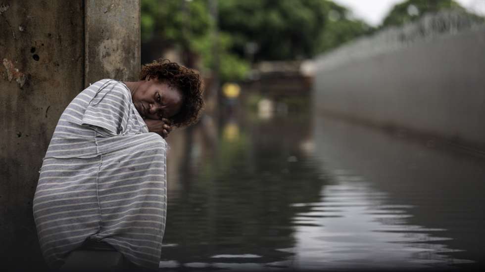 epaselect epa10456741 A woman stands on a flooded area following heavy rains since 07 of February in Maputo, Mozambique, 09 February 2023. About 2,400 families were left homeless, and dozens of houses flooded in the Mozambican capital.  EPA/LUISA NHANTUMBO
