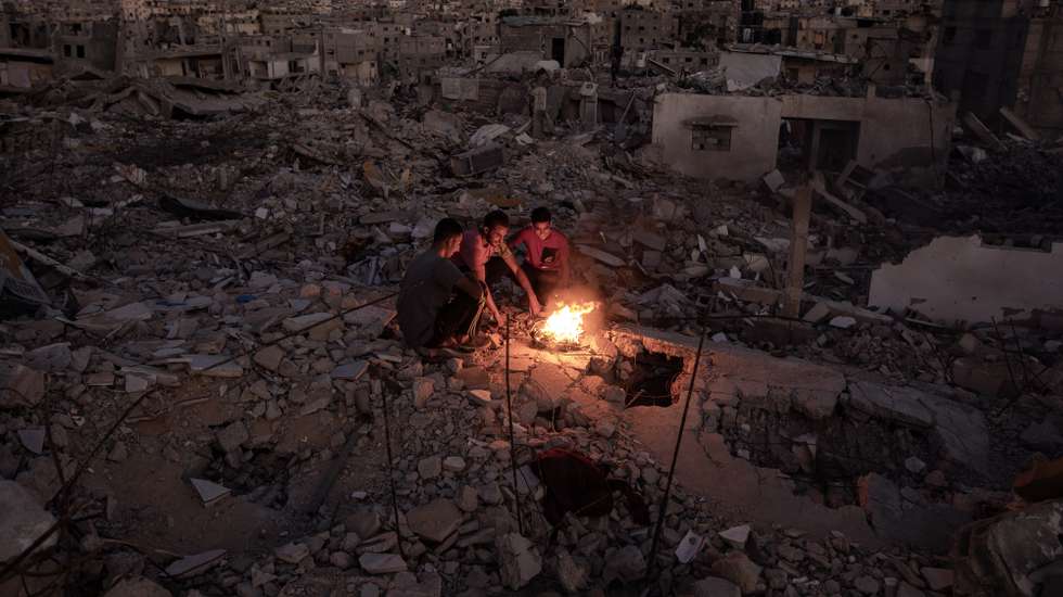 epaselect epa11671648 Palestinians sit next to a fire on the rubble of their destroyed home in Khan Yunis, southern Gaza Strip, 20 October 2024. More than 42,500 Palestinians and over 1,400 Israelis have been killed, according to the Palestinian Health Ministry and the Israel Defense Forces (IDF), since Hamas militants launched an attack against Israel from the Gaza Strip on 07 October 2023, and the Israeli operations in Gaza and the West Bank that followed it.  EPA/HAITHAM IMAD