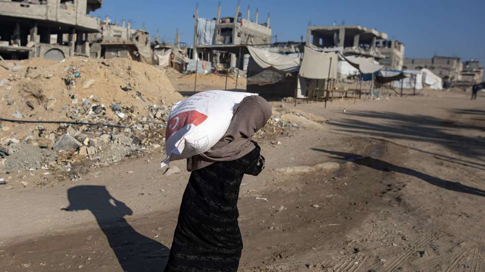 epa11754053 A Palestinian woman carries a bag of flour after receiving food aid at a distribution center of the United Nations Relief and Works Agency for Palestine Refugees in the Near East (UNRWA) in Khan Younis, southern Gaza Strip, 03 December 2024. According to the UN, over 1.8 million people across the Gaza Strip are experiencing 'high levels' of acute food insecurity, including around 133,000 people facing 'catastrophic' food insecurity, with acute malnutrition ten times higher than before the war.  EPA/HAITHAM IMAD