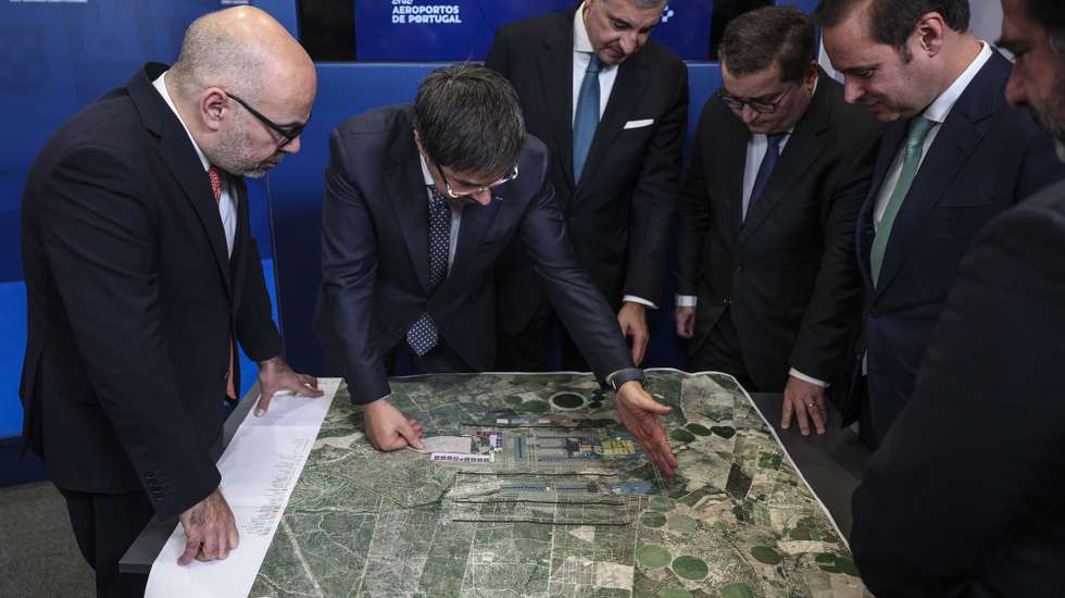 O ministro das Infraestruturas e Habitação, Miguel Pinto Luz (E), o ministro de Estado e das Finanças, Joaquim Miranda Sarmento (3-D), o presidente da ANA, José Luis Arnaut (3-E), e o presidente executivo da ANA, Thierry Ligonnière (2-E), observam o plano do aeroporto após receberem o Relatório Inicial (High Level Assumption Report) da concessionária ANA sobre o desenvolvimento da capacidade aeroportuária de Lisboa,  para iniciar formalmente negociações sobre a extensão do contrato de concessão e viabilizar a construção do novo Aeroporto Luís de Camões, em Alcochete, 17 de dezembro de 2024.  ANDRÉ KOSTERS/LUSA