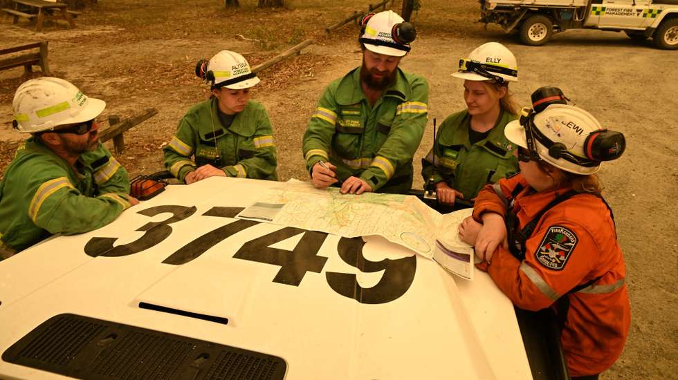 epa11789197 Forest Fire Management Victoria personnel are seen looking at a map on the boot of a vehicle near the fire zone outside of in Halls Gap, Victoria, Australia, 22 December 2024. Immediate evacuation orders are in place for towns across Victoria as out-of-control blazes and sweltering temperatures begin Australia's bushfire season.  EPA/JAMES ROSS AUSTRALIA AND NEW ZEALAND OUT