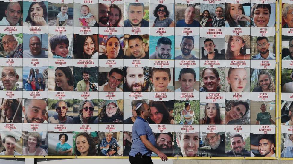 epa11760216 People walk past a billboard showing pictures of Israeli hostages held by Hamas in Gaza, in Tel Aviv, Israel, 06 December 2024. According to the Israeli army (IDF), around 100 Israeli hostages remain in captivity in the Gaza Strip, including bodies of 33 confirmed dead.  EPA/ABIR SULTAN