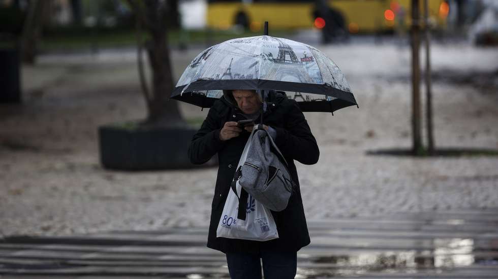Mulher com chapéu de chuva na Costa de Caparica, Almada, 4 de novembro de 2024. CARLOS M. ALMEIDA/LUSA