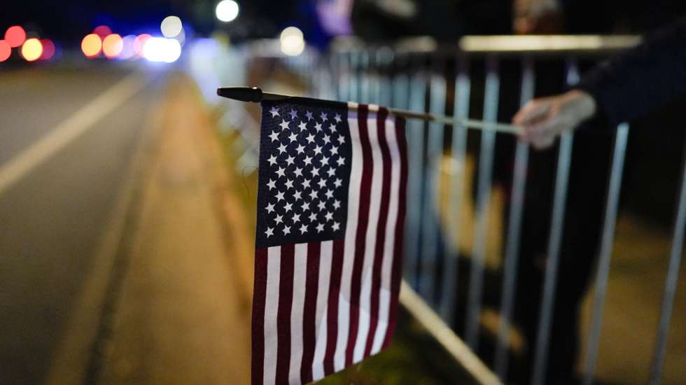 epa11816131 A person holds a flag as the hearse carrying the casket of former President Jimmy Carter moves through downtown to the Carter residence for his interment in Plains, Georgia, USA, 09 January 2025. Carter, the 39th US president, died at age 100, 29 December 2024.  EPA/Mike Stewart / POOL
