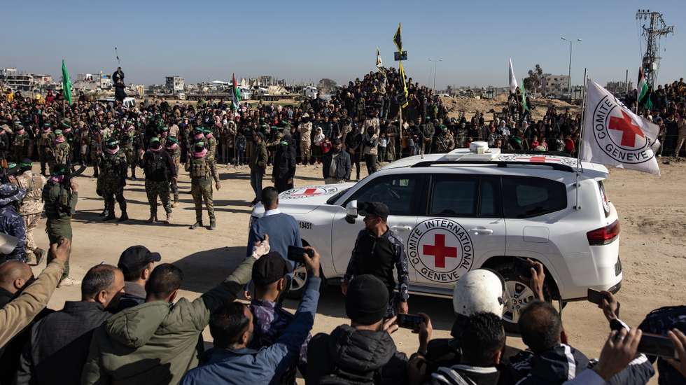 epaselect epa11897702 Palestinians and Izz ad-Din al-Qassam brigade fighters stand around Red Cross vehicles during the handover ceremony of three Israeli hostages to the Red Cross, in Khan Yunis, southern Gaza Strip, 15 February 2025. Hamas on 15 February released three Israeli hostages in exchange for 369 Palestinians detained in Israeli prisons. Israel and Hamas implemented the first phase of a hostage release and ceasefire deal on 19 January 2025.  EPA/HAITHAM IMAD