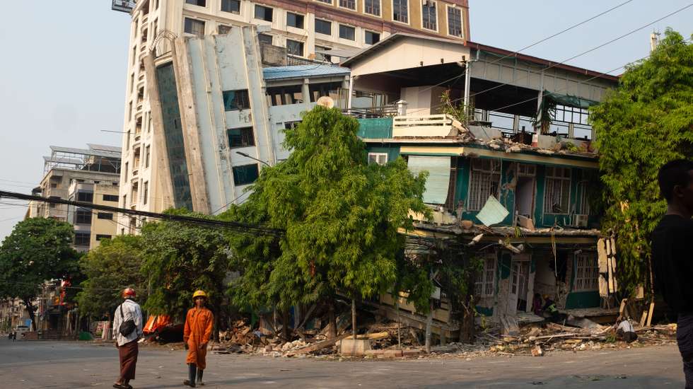 epa11996766 Rescuers walk in front of a damaged building following an earthquake in Mandalay, Myanmar, 29 March 2025. More than 1,000 people have been killed and thousands injured after a 7.7-magnitude earthquake struck the country on 28 March, according to the Myanmar government.  EPA/STRINGER
