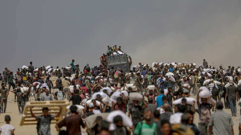 epa12290463 Internally displaced Palestinians carry bags of flour near a food distribution point in Zikim, northern Gaza Strip, 08 August 2025. Humanitarian organizations have warned of an imminent food catastrophe for thousands of children, a crisis caused by severe food insecurity, a decline in health services, and ongoing restrictions on humanitarian aid and essential supplies.  EPA/MOHAMMED SABER