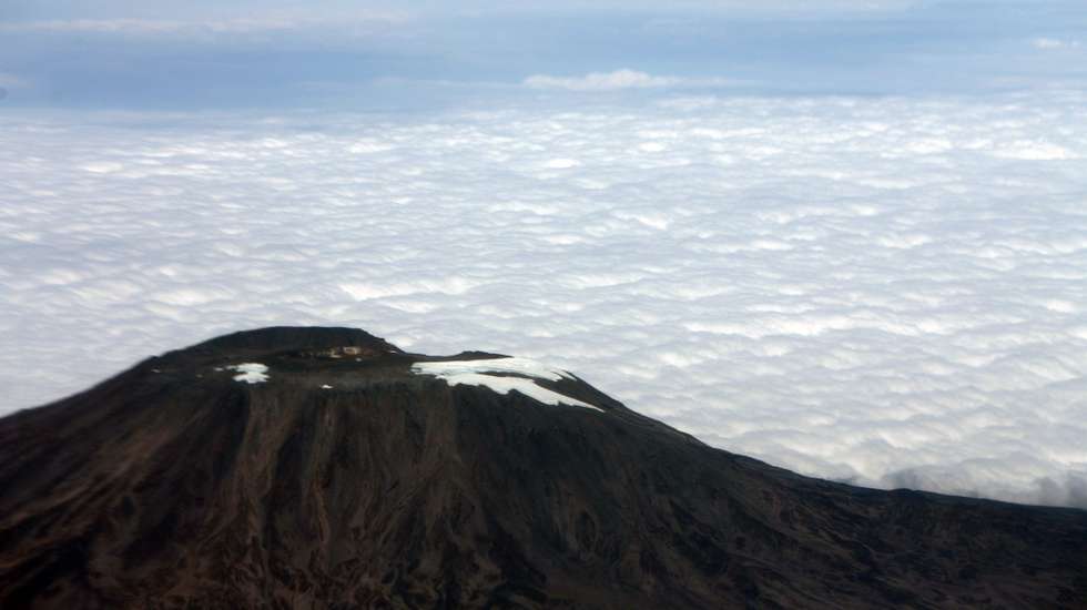 epa01788496 (FILE) In this 30 June 2009 photo of Mount Kilimanjaro in Tanzania taken from a commercial aircraft, the absence of large glaciers is clearly evident. AT 5,895 meters, the extinct volcano in northern Tanzania near the equator, Mt. Kilimanjaro is the highest mountain in Africa - famous for its snow-capped peaks and large glaciers which have shrunk 82 percent since 1912. Climate change and forest depletion near the mountain are both blamed for the melt-off. On 08 July 2009 the G8 Summut leaders agreed for the first time to the goal of keeping the world's average temperature from rising more than 2C.  EPA/STEPHEN MORRISON