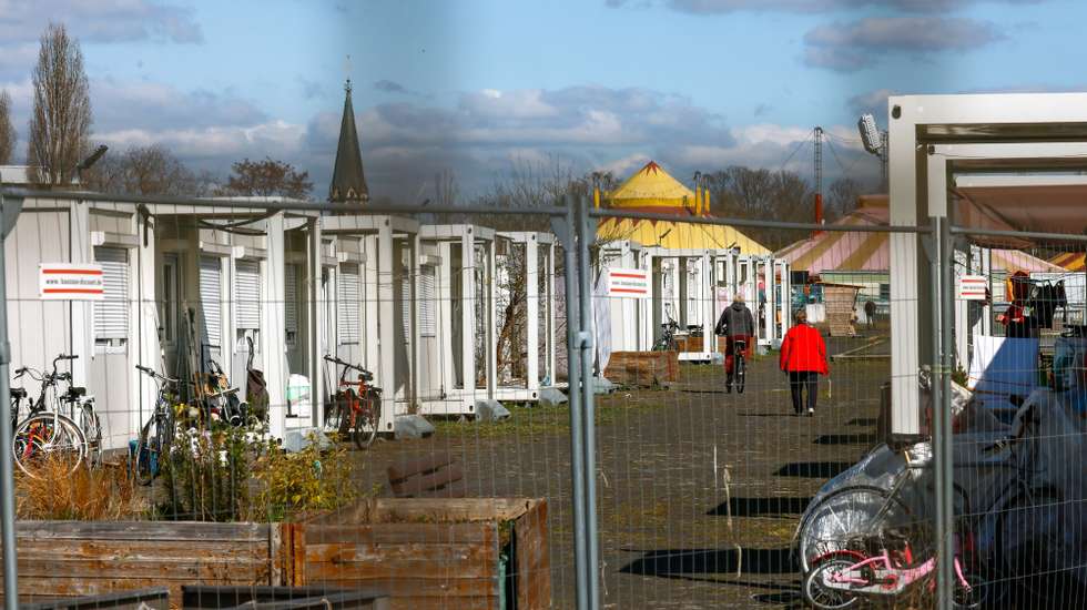 epa12003147 People pass by containers used for housing refugees at the former Berlin-Tempelhof airport, in Berlin, Germany, 01 April 2025. German acting Interior Minister Nancy Faeser presented an assessment of the outgoing federal government's migration policy, highlighting the progress made.  EPA/HANNIBAL HANSCHKE
