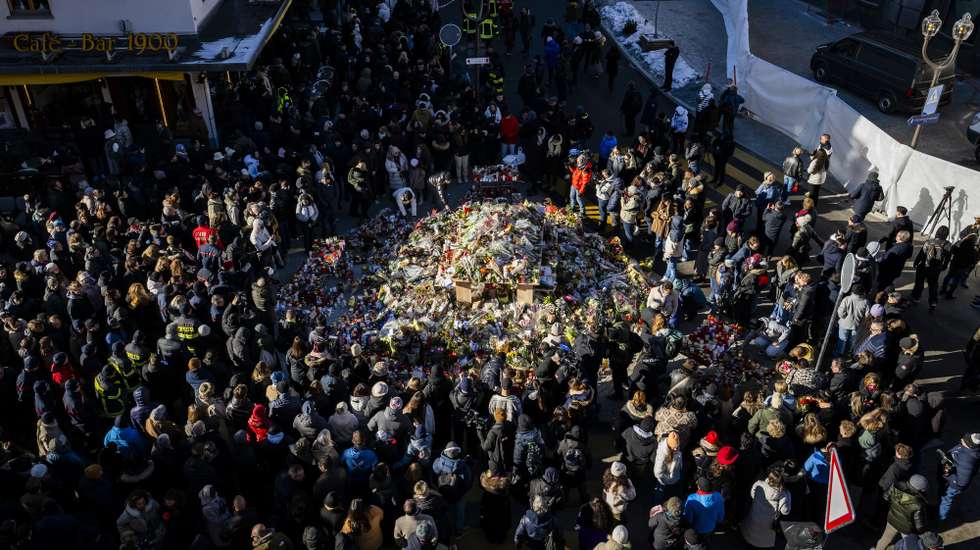 epa12625457 Mourners gather around flowers and candles to commemorate the victims of the fire at the "Le Constellation" bar and lounge, in Crans-Montana, Switzerland, 04 January 2026. At least 40 people lost their lives and over 100 were severely injured in the fire that devastated the bar 'Le Constellation' on New Year's Eve in the Swiss Alps resort of Crans-Montana.  EPA/JEAN-CHRISTOPHE BOTT