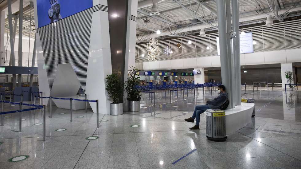 epa08839510 A commuter stands in the empty departure terminal next to a poster depicting the ancient goddess Athena, at Eleftherios Venizelos International Airport of Athens, during the second lockdown of the country, in Spata, near Athens, Greece, 24 November 2020. Greece is currently under a nationwide lockdown that went into effect on November 7 and will remain effective through November 30, to prevent the spread of the coronavirus Covid-19 pandemic.  EPA/YANNIS KOLESIDIS