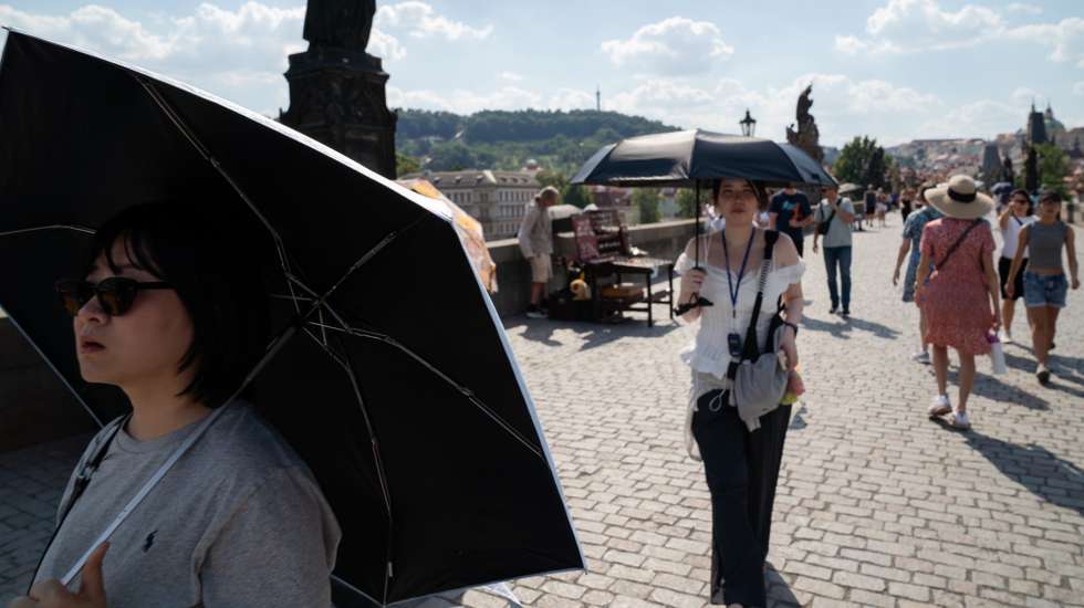 epa13064313 People walk on the Charles bridge with umbrellas to shelter from the heat on a sunny day in Prague, Czech Republic, 25 June 2026. Meteorologists expect that the Czech absolute temperature record of 40.4 degrees may be broken this weekend.  EPA/Fadi Yousef