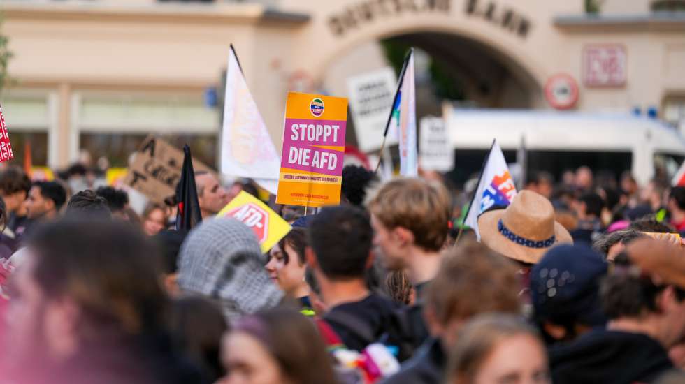 epa13085120 A demonstrator holds a sign depicting a crossed-out AfD logo and the word 'resist' as people gather in front of the main train station in Erfurt, Germany, 04 July 2026, ahead of the Alternative for Germany (AfD) federal congress. The AfD is holding its 17th Federal Party Congress on 04 and 05 July in Erfurt.  EPA/CHRISTOPH RUTENKOLK