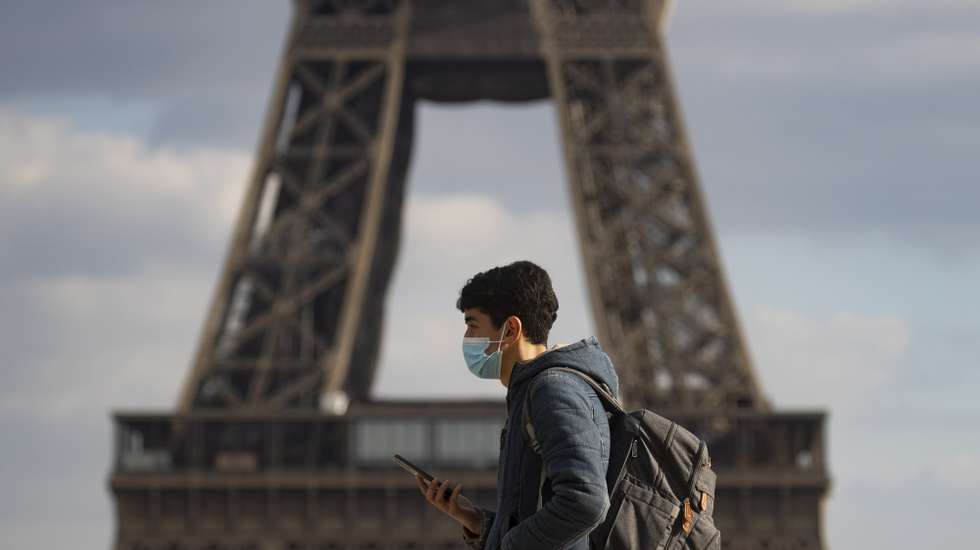 epa09038487 Pedestrians wearing face masks walk near the Eiffel Tower in Paris, France, 26 February 2021. Paris City Hall suggests a third lockdown,  for three weeks, to curb the rate of Covid-19 coronavirus infections.  EPA/IAN LANGSDON