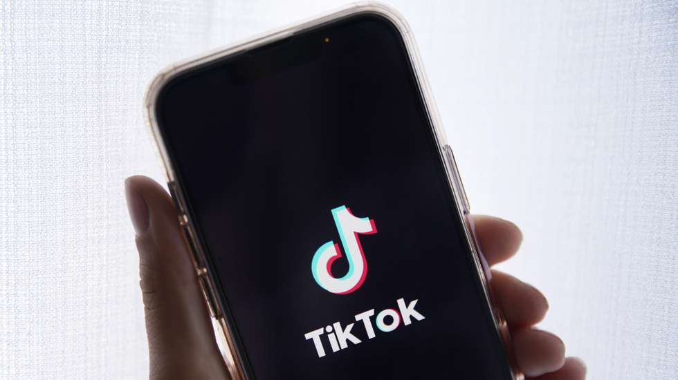 epa10635388 In this photo illustration a person holds up a cell phone with the TikTok logo displayed in Los Angeles, California, USA, 17 May 2023. Govenor Greg Gianforte of Montana signed a measure that bans the TikTok app in the state.  EPA/CAROLINE BREHMAN
