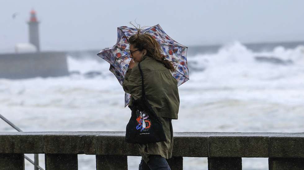 Uma mulher tenta proteger-se da chuva e do vento na marginal da Foz do Douro no Porto, 17 de outubro de 2023. Mais de 40 ocorrências foram registadas desde as 00:00 de hoje, a maioria na Grande Lisboa e em Setúbal, devido ao mau tempo, segundo informação disponível no ‘site’ da Autoridade Nacional de Emergência e Proteção Civil (ANEPC). ESTELA SILVA/LUSA