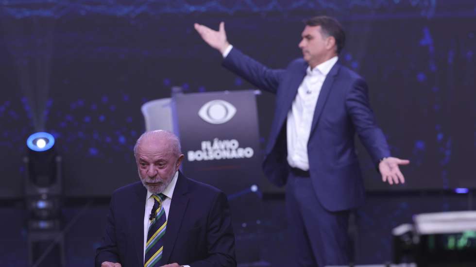 epa13314646 The President of Brazil and candidate for reelection, Luiz Inacio Lula da Silva (L), and opposition candidate Flavio Bolsonaro speak during the first presidential debate at the Rede Bandeirantes headquarters in Sao Paulo, Brazil, 18 October 2026. Lula attacked Bolsonaro by linking him to Argentine President Javier Milei and US President Donald Trump; meanwhile, the opposition candidate responded by connecting his opponent to Nicaraguan Head of State Daniel Ortega and deposed Venezuelan president Nicolas Maduro.  EPA/SEBASTIAO MOREIRA