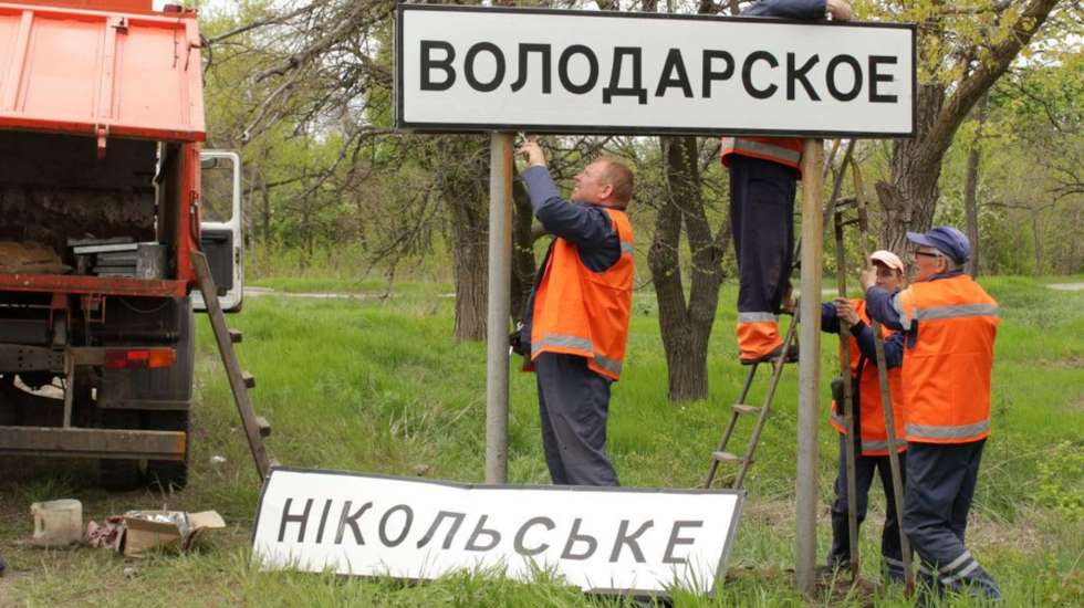 No chão, caída, vê-se uma placa que diz Nikolske. Agora, volta a ter uma placa com o nome do tempo da União Soviética, Volodarske