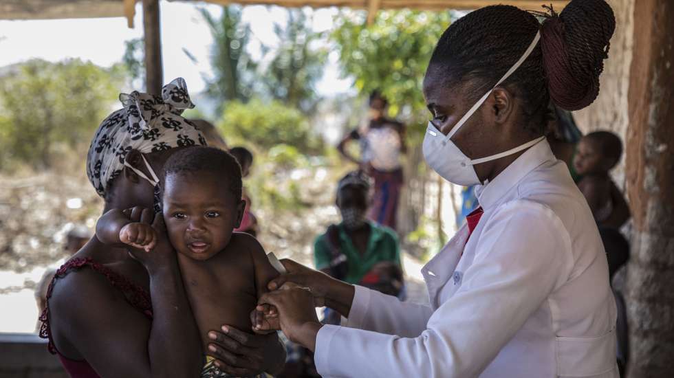 Uma criança é examinada pela técnica de nutrição, Amélia Mindulll (D), durante uma consulta de uma brigada móvel do Fundo das Nações Unidas para a Infância (UNICEF), um grupo de profissionais de saúde que viaja de ambulância e vai ao encontro das comunidades mais afastadas em vez de esperar por elas em centros de saúde, Impire, Moçambique, 24 de julho de 2020. Em menos de uma hora, na povoação de Impire, distrito de Metuge, sul de Cabo Delgado, juntam-se dezenas de mães com as suas crianças - a maioria ainda bebés - para a brigada observar, com pesagem, medição de altura, avaliação à subnutrição, seguindo-se uma consulta, vacinação e entrega da medicamentos numa rotina que inclui a observação das mães e decorre desde manhã até o sol se pôr, num pavilhão empoeirado. (ACOMPANHA TEXTO DE 25 DE JULHO DE 2020). RICARDO FRANCO/LUSA