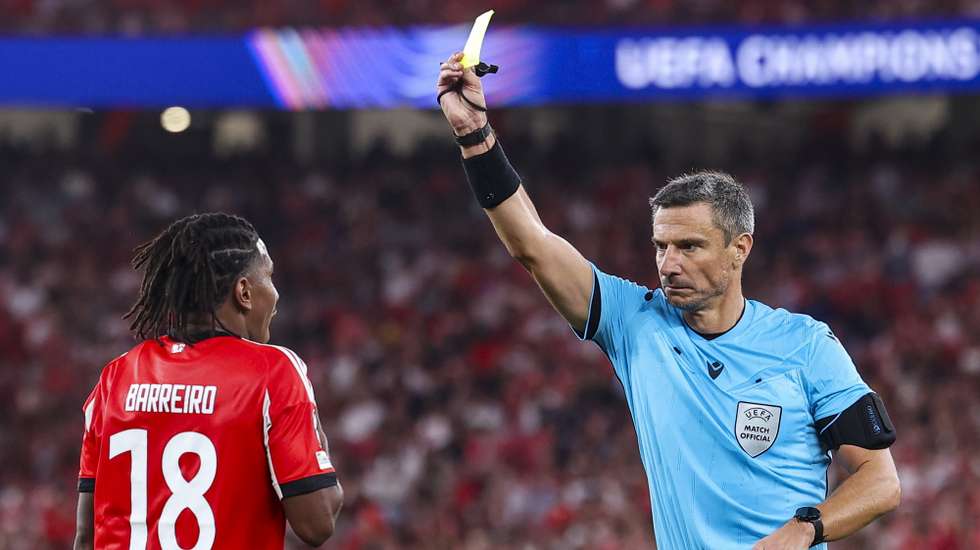 epa12328240 Referee Slavko Vincic shows a yellow card to Benfica's Leandro Barreiro (L) during the UEFA Champions League play-offs second leg soccer match between SL Benfica and Fenerbahce SK, in Lisbon, Portugal, 27 August 2025.  EPA/JOSE SENA GOULAO