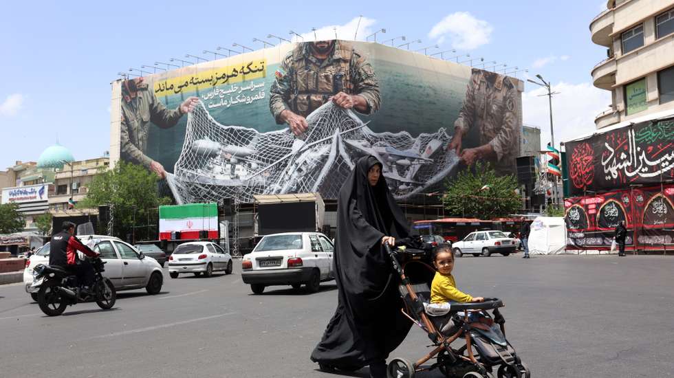 epa12940977 An Iranian woman walks next to a huge anti-US billboard carrying a sentence reading in Persian ’The Strait of Hormuz remains closed’ at the Engelab (Revolution) square in Tehran, Iran, 08 May 2026. Iran and US exchanged fire in the Strait of Hormuz amid a ceasefire.  EPA/ABEDIN TAHERKENAREH