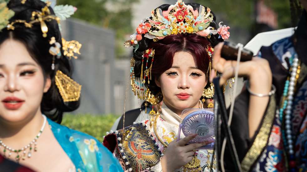 epa13257174 A person wearing traditional clothing uses an electric fan in Beijing, China, 23 September 2026.  EPA/JESSICA LEE