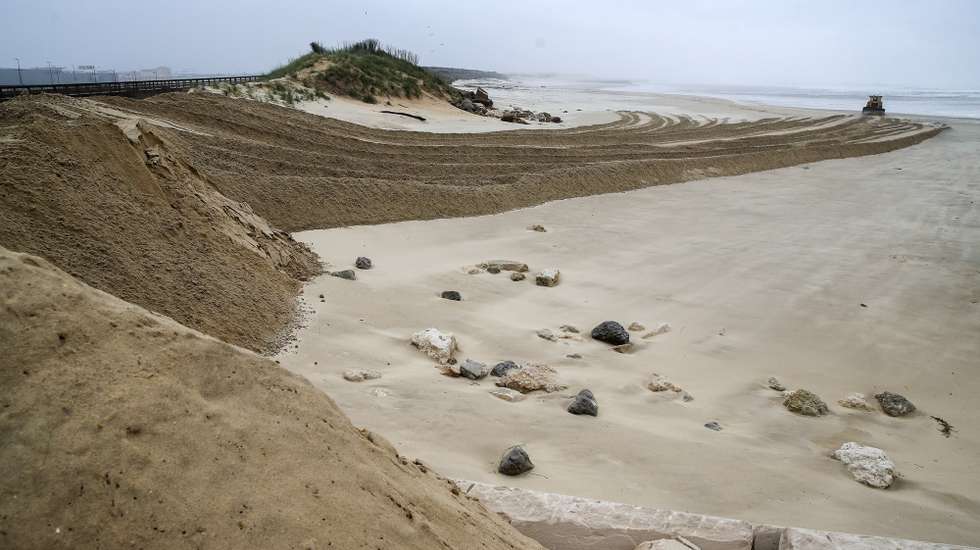 Uma máquina de rastos faz uma barreira com areia para proteger as construções do avanço da água do mar, na Praia do Cabedelo, Figueira da Foz, 24 de novembro de 2022. Na zona do Cabedelo, onde os galgamentos são frequentes, os serviços municipais de Proteção Civil colocaram desde quarta-feira uma máquina de rastos na praia a erguer uma barreira de areia para travar a invasão do mar, que vai continuar a trabalhar ao longo do dia. PAULO NOVAIS/LUSA