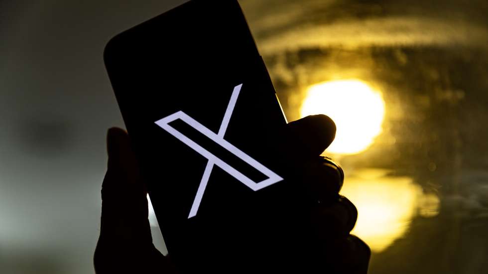 epa10772440 An illustration pictures shows a user holding a mobile phone displaying the 'X' logo, in Los Angeles, California, USA, 27 July 2023. Twitter announced on 23 July that it will rebrand to X.  EPA/ETIENNE LAURENT