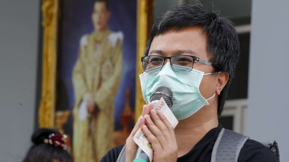 epa08925759 Pro-democracy protest leader Anon Nampa stands in front of a portrait of Thai King Maha Vajiralongkorn Bodindradebayavarangkun while thanking supporters for gifting him 1,000 baht (27 euro) outside the Pathum Wan police station in Bangkok, Thailand, 08 January 2021. Anti-government protest leaders Anon Nampa and Panupong Jadnok presented themselves to the police to hear charges for organizing anti-government rallies during the emergency decree in 2020.  EPA/DIEGO AZUBEL