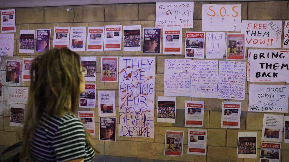 epa10919216 A person looks at pictures of hostages hanging on a wall during a protest calling on the Israeli government to help rescue the hostages held by Hamas militants in Gaza, outside the Kirya military base in Tel Aviv, Israel, 14 October 2023. More than 1,300 Israelis have been killed and over 3,200 others injured, according to the IDF, after the Islamist movement Hamas launched an attack against Israel from the Gaza Strip on 07 October. More than 2,000 Palestinians have been killed and over 8,700 others injured in Gaza since Israel launched retaliatory air strikes, the Palestinian health ministry said.  EPA/ABIR SULTAN