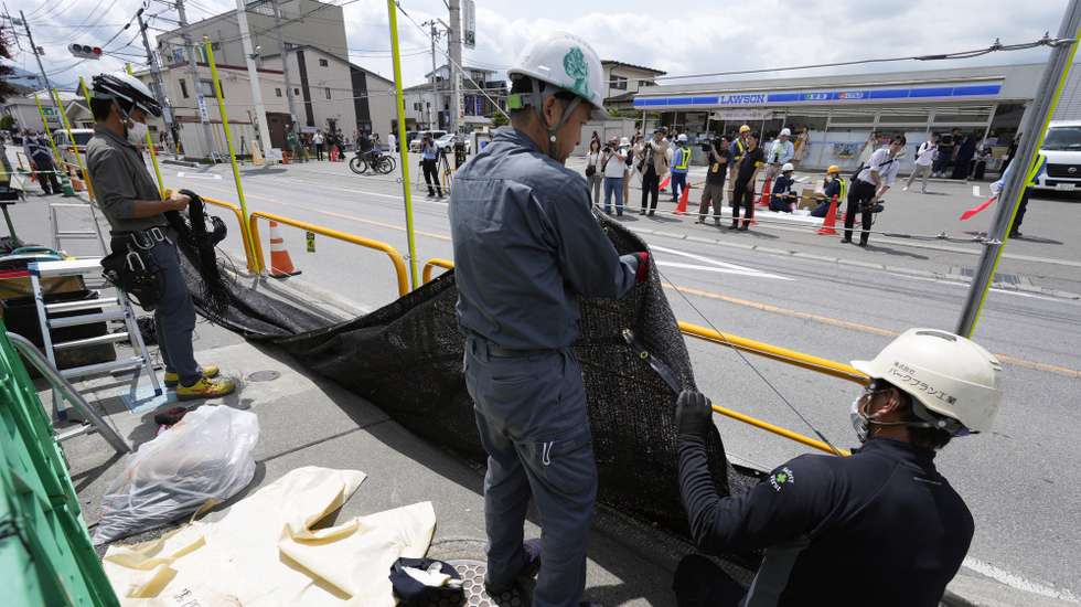 epa11356932 Workers install a black shading net on the opposite side of the Lawson Kawaguchiko Ekimae convenience store in Fujikawaguchiko, north of Mount Fuji, Japan, 21 May 2024. The town of Fujikawaguchiko, north of Mount Fuji, installed a black shading net to block the view of Japan's iconic volcano from a particular spot before the Lawson Kawaguchiko Ekimae convenience store that became popular in the last two years to deter tourists who crowd there to photograph it following complains from locals.  EPA/FRANCK ROBICHON