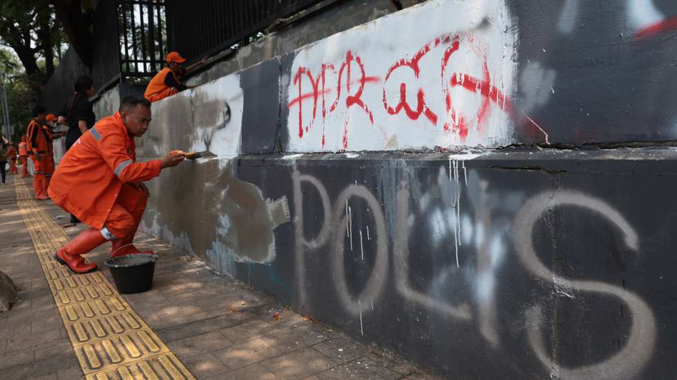 Workers remove graffiti with paint after massive protests  in front of Parliament building  in Jakarta, Indonesia, 01 September 2025. Protests erupted across the country following the death of a motorbike hailing driver during an earlier protest against the housing allowance for members of parliament on the night of 28 August in Jakarta
