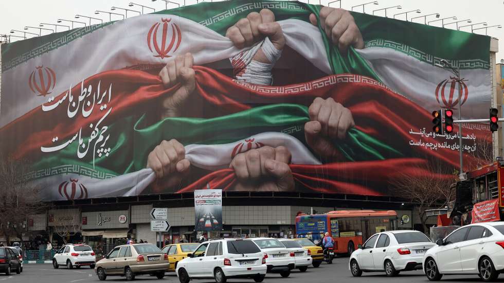 epa12646181 Iranians drive past a billboard reading 'Iran is our Homeland' at Enqelab Square in Tehran, Iran, 13 January 2026. Iran is experiencing a nationwide internet blackout that began on 08 January 2026, amid an intensifying wave of anti-government protests.  EPA/ABEDIN TAHERKENAREH