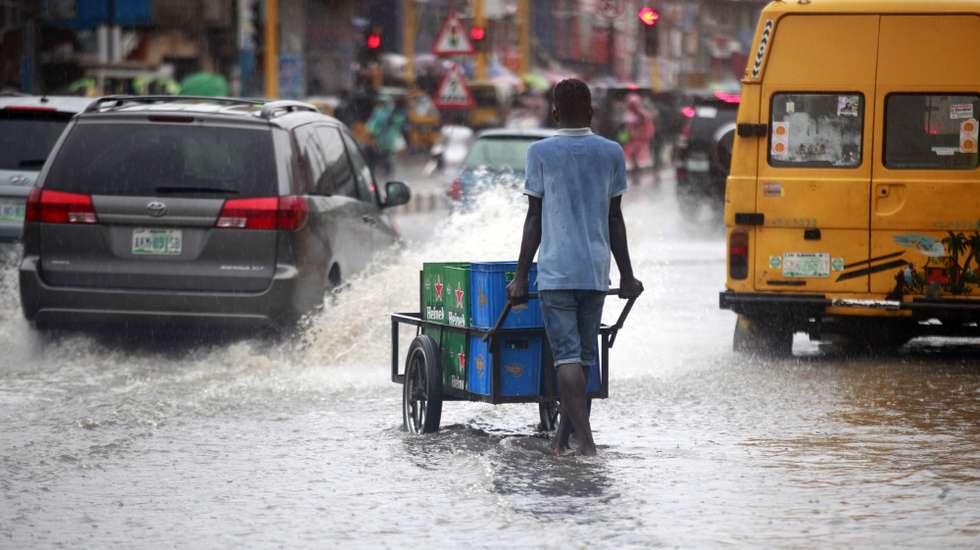 epa10595409 A boy pushes a cart through a flooded road after rain, causing heavy traffic in Lagos, Nigeria 27 April 2023.  EPA/Akintunde Akinleye